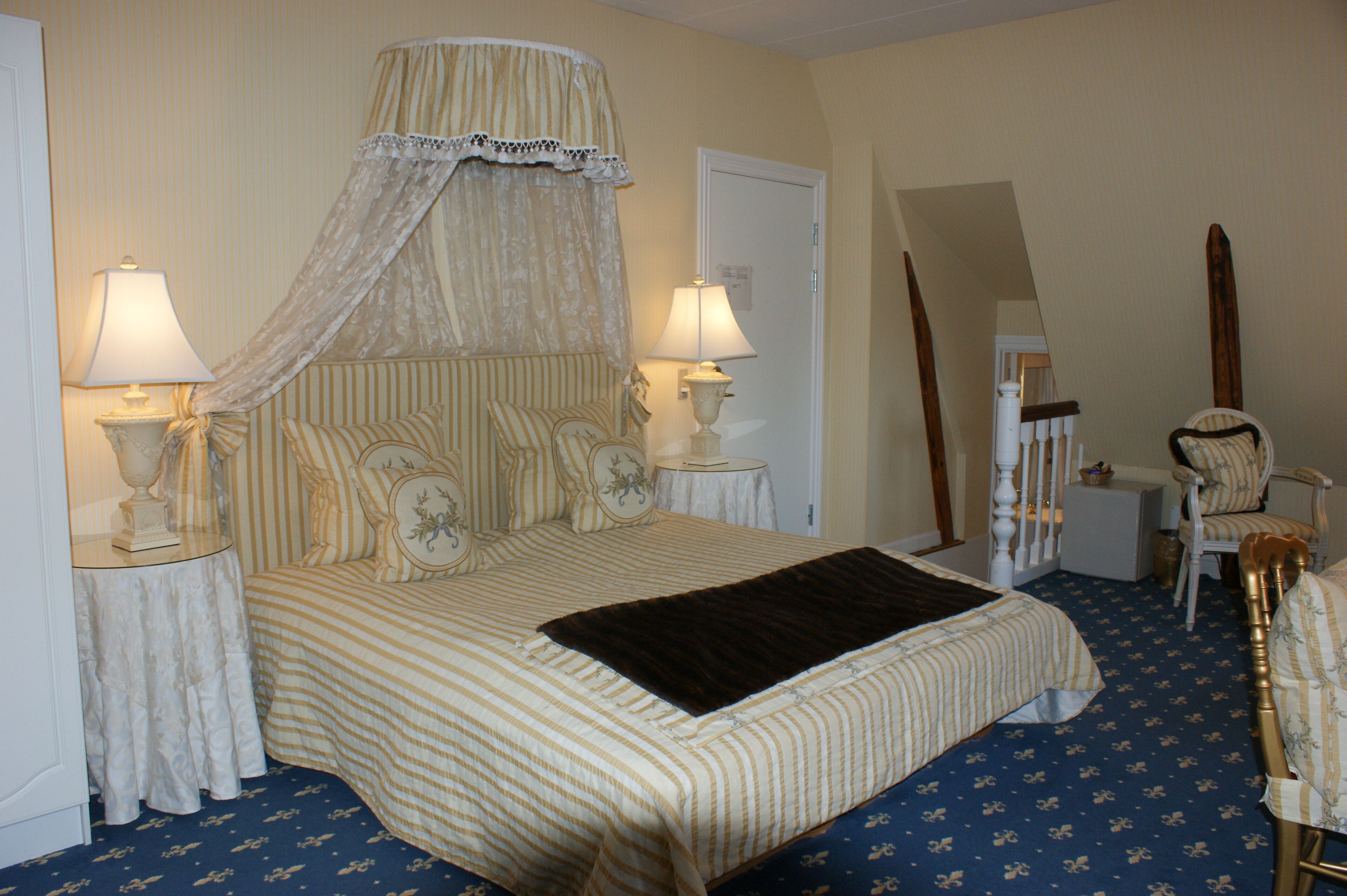 Une chambre à coucher avec un grand lit, deux tables de chevet avec des lampes, une chaise et un miroir.