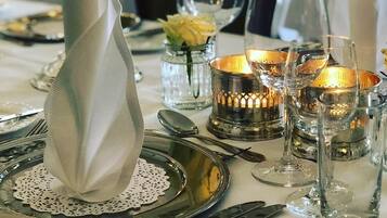 A table set with silverware, plates, and glassware, accompanied by candles and a folded napkin.