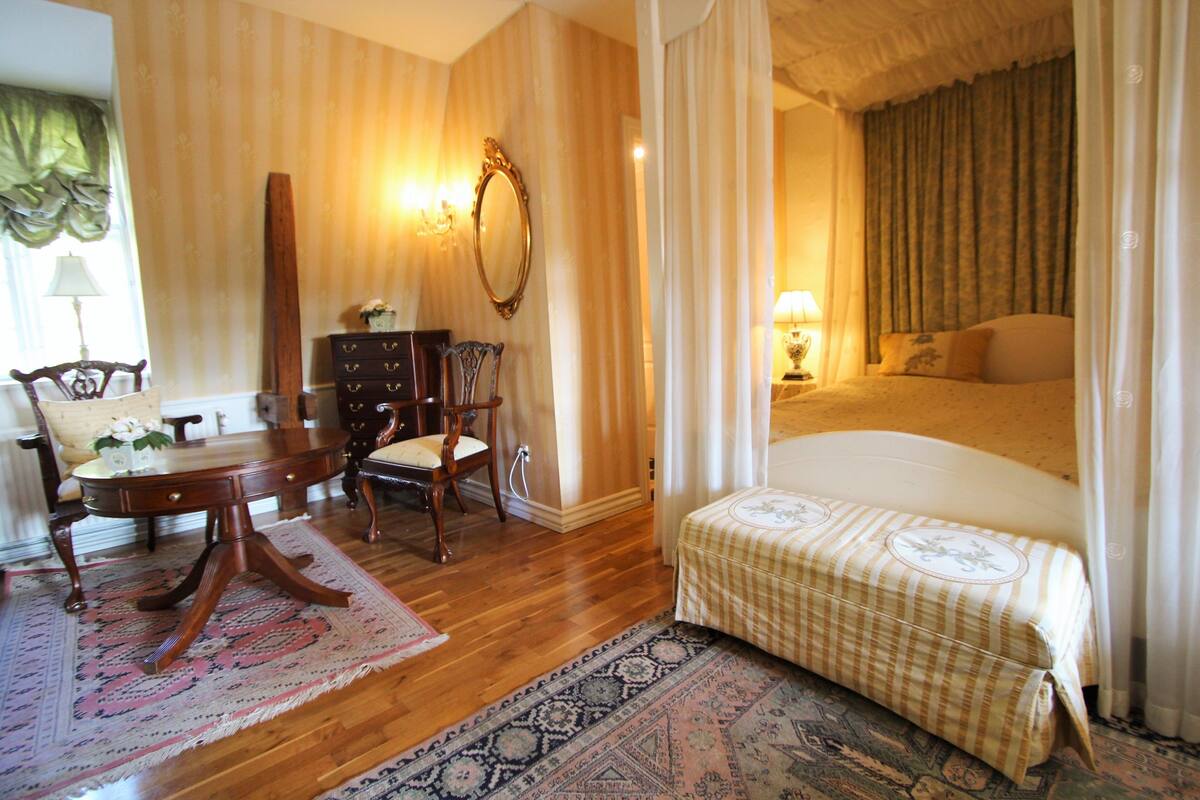 A room with a bed, a desk with chairs, a dresser, and a mirror.
