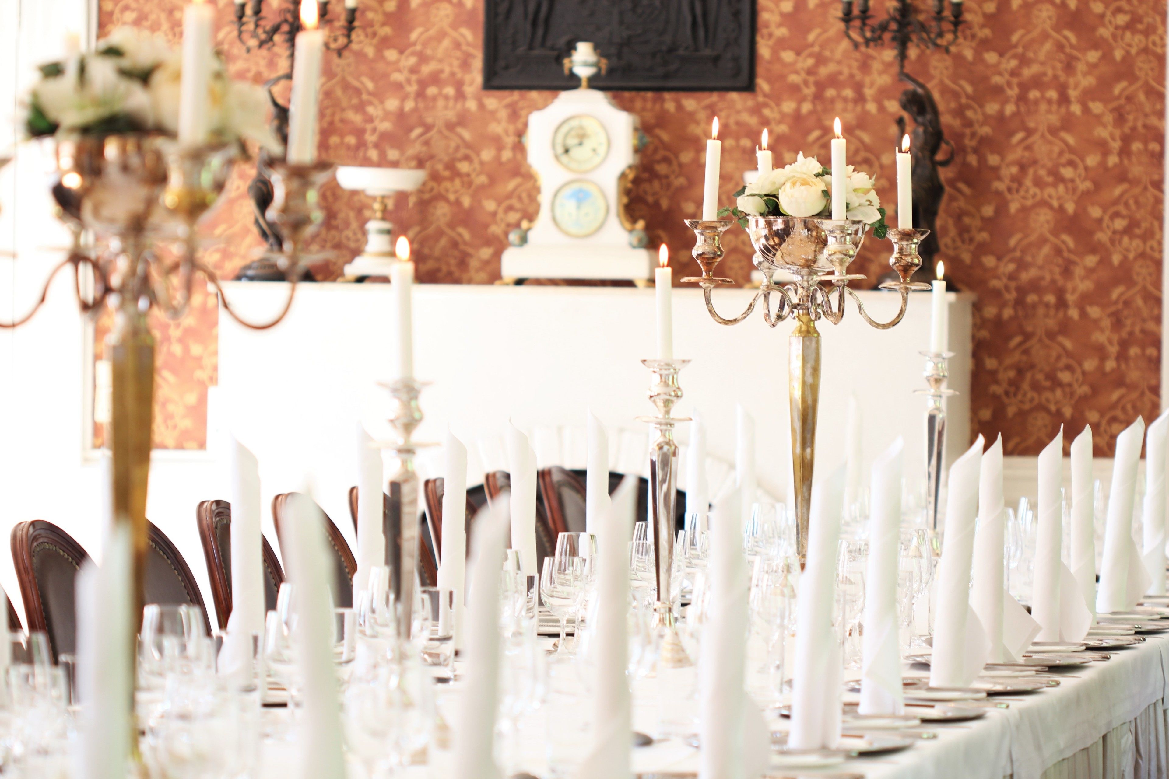 A formal dining table set with white candles, glassware, and elegant tableware.