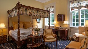 A four-poster bed with floral curtains, a wooden desk, two chairs, and a chandelier. - Sophiendal Slotshotel (Skanderborg)