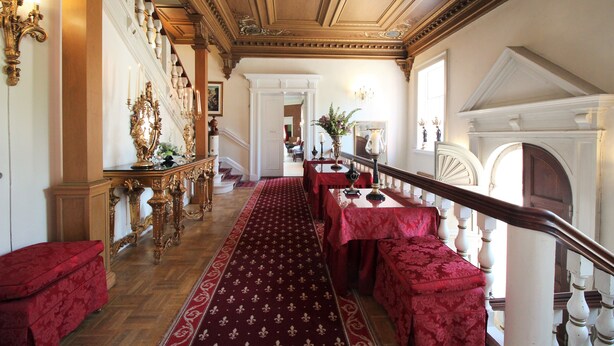 A grand hallway with ornate chandeliers, a red carpet, and a staircase leading to another level. - Sophiendal Slotshotel (Skanderborg)
