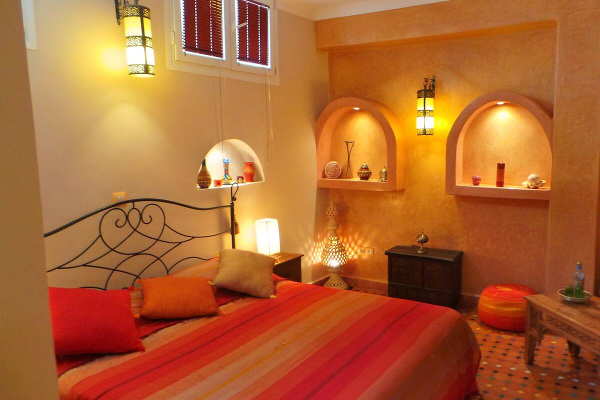 A hotel room with a bed, a nightstand, a lamp, and a small table with a tissue box.