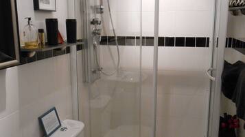 Un baño con ducha de vidrio, inodoro y lavamanos.