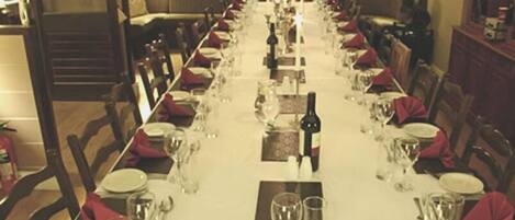 A long dining table set for a meal with chairs on both sides.
