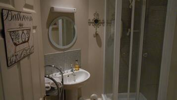 Un baño con lavamanos, espejo y ducha.
