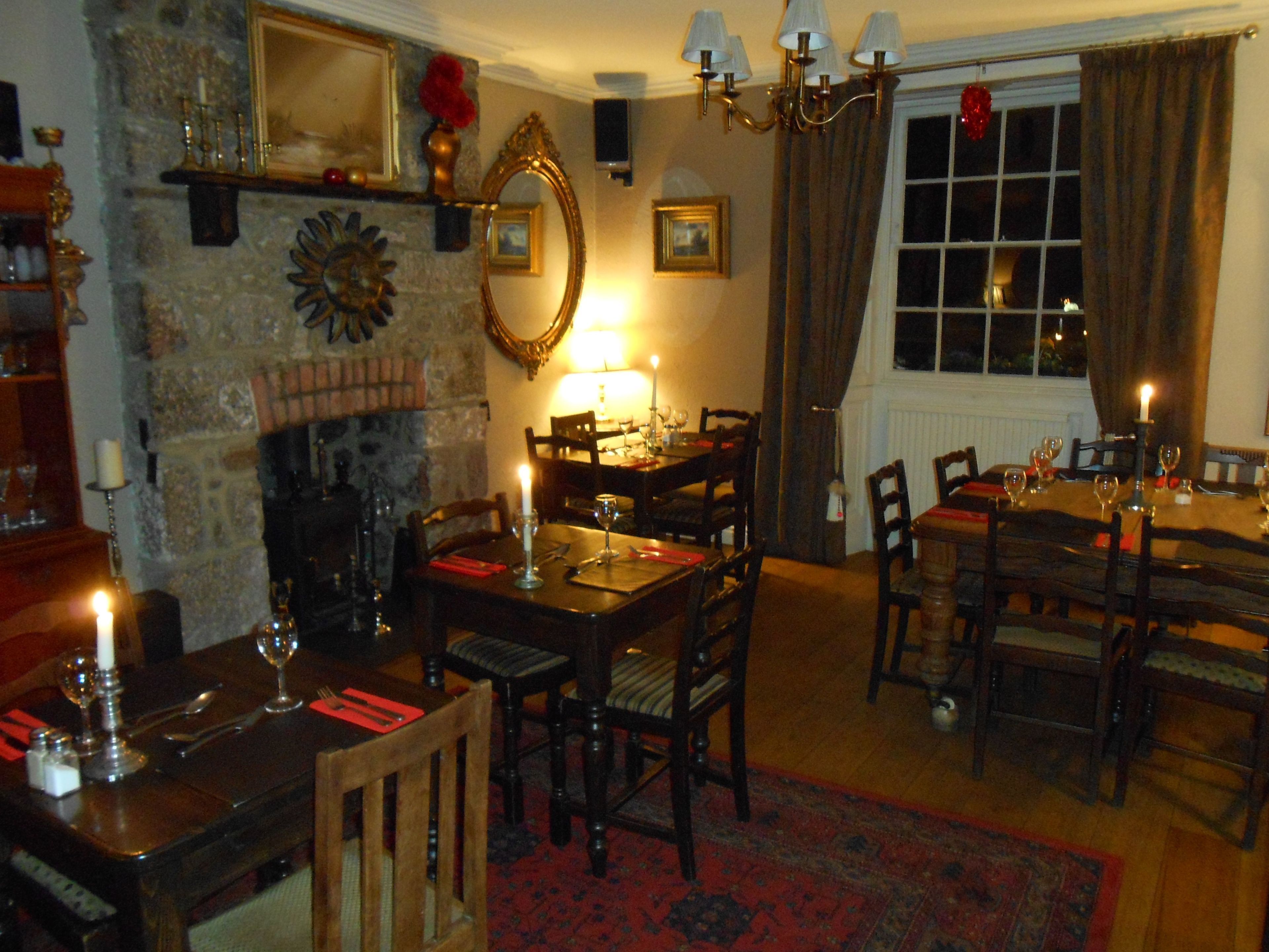 A dining area with a fireplace, wooden furniture, and a chandelier.