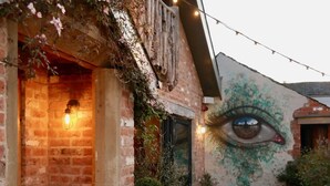 A courtyard with a brick building, a large eye mural, string lights, and potted plants. - The Cartford Inn (Preston)
