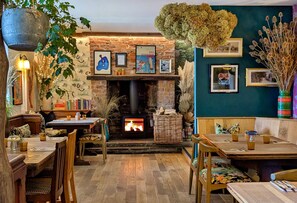 A cozy interior with a brick fireplace, wooden furniture, and various wall decorations.