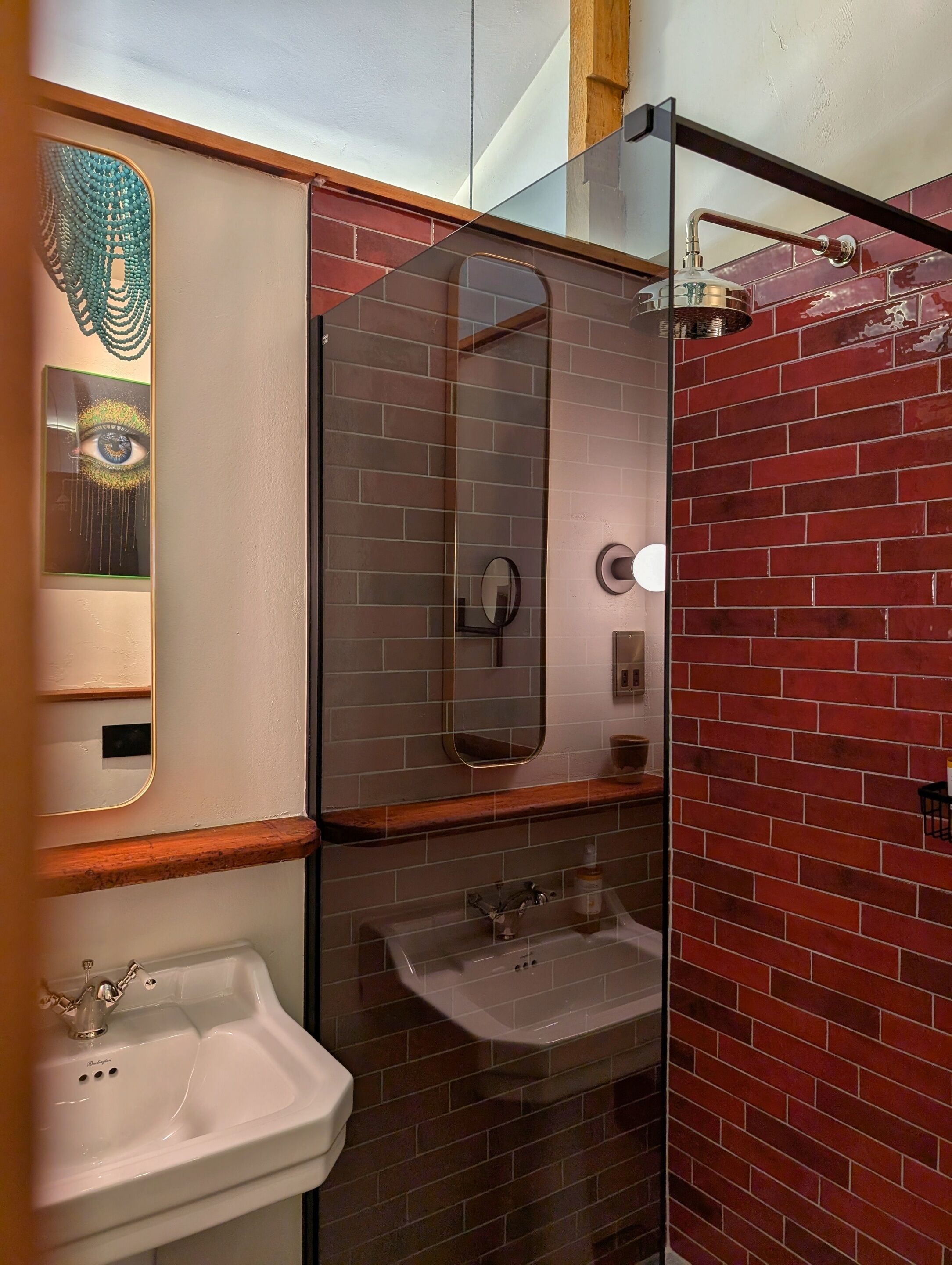 A bathroom with a mirror, two sinks, and a shower area.
