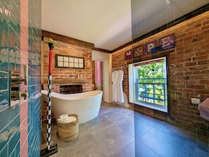 A modern bathroom with a freestanding bathtub, a brick wall, and a large window. - The Cartford Inn (Preston)