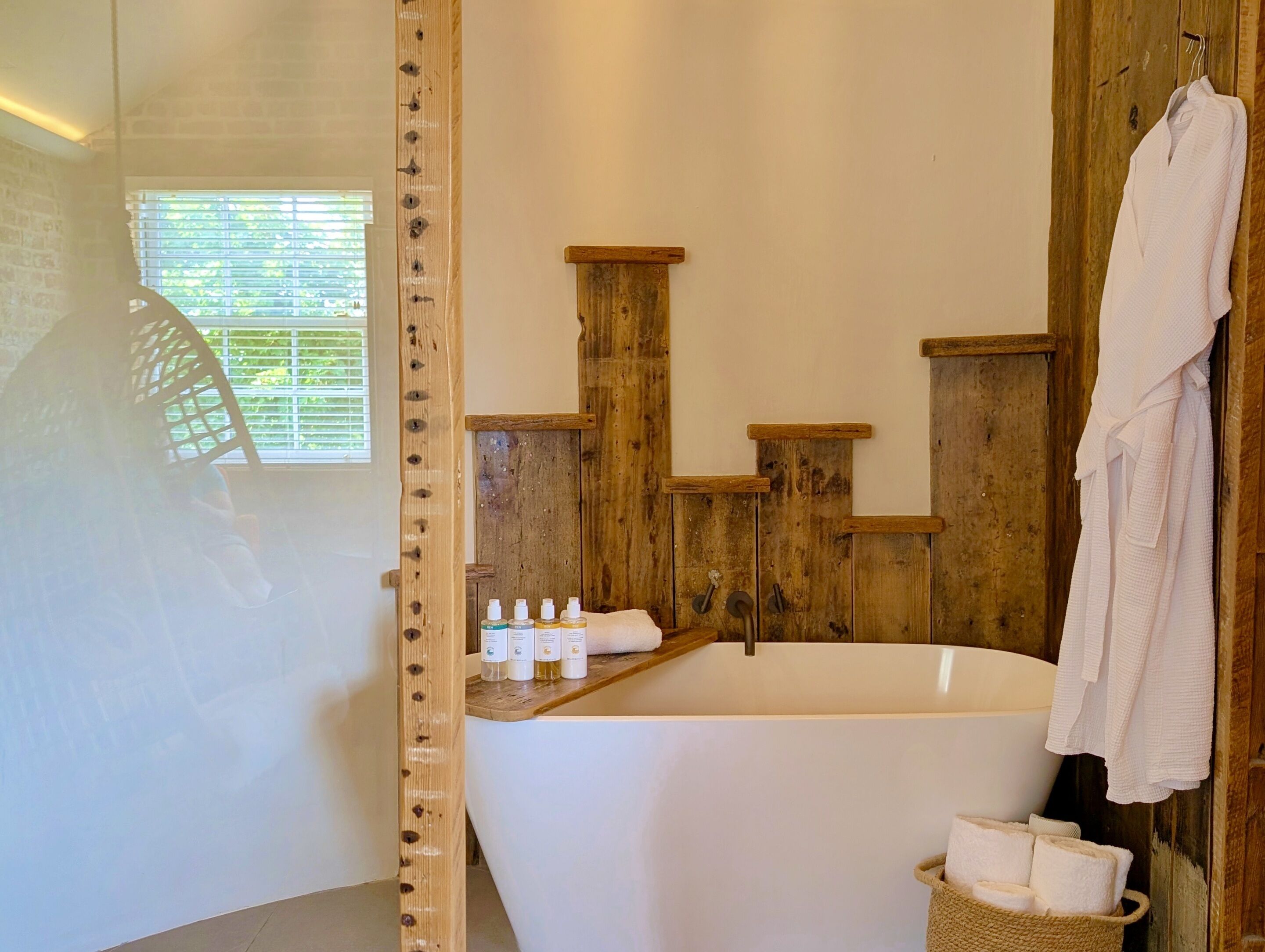 Un baño con pared de madera, una bañera y un estante con artículos de tocador.