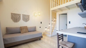 Un salon moderne avec un canapé, un coin repas doté d’un bar et un escalier menant à un niveau supérieur.