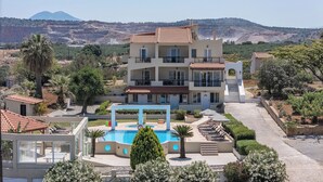 Un hôtel à plusieurs étages doté d’une piscine, entouré de verdure et avec des montagnes en toile de fond.