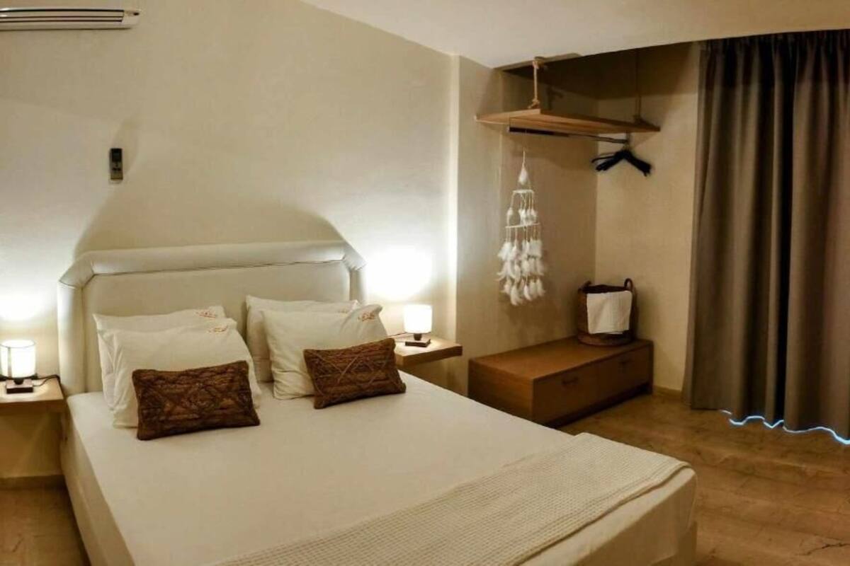 Una habitación de hotel con cama, mesitas de noche, lámpara colgante, armario y cortina.