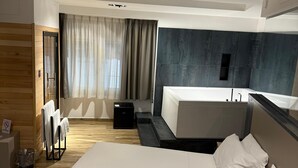 A modern hotel room with a large bed, a desk, and a shower area. - Golden Hotel (Naples)