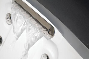 Primer plano de un grifo cromado con agua corriendo en un lavamanos.