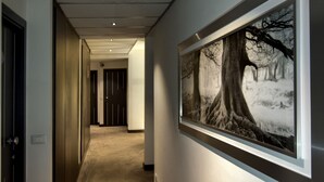 A hallway with a framed photograph of a forest scene on the wall. - Golden Hotel (Naples)