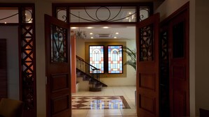 Un hall d’hôtel avec un escalier, des portes en bois et un sol à motifs.