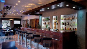 Un espace bar avec un comptoir, des tabourets et des étagères remplies de bouteilles d’alcool.