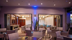 Un hall d’hôtel moderne avec un espace repas aménagé avec des meubles en osier et une table centrale.