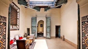 A spacious room with a high ceiling, a sofa set, a dining table, and a view through an open doorway. - Dar Bensouda (Fes)