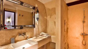 A bathroom with a large mirror, a white sink, a towel rack, and a shower.