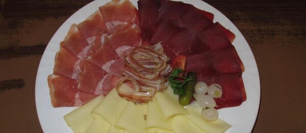 A plate with various meats, cheese, and vegetables. - Hotel Restaurant Mattmarkblick (Saas Almagell)