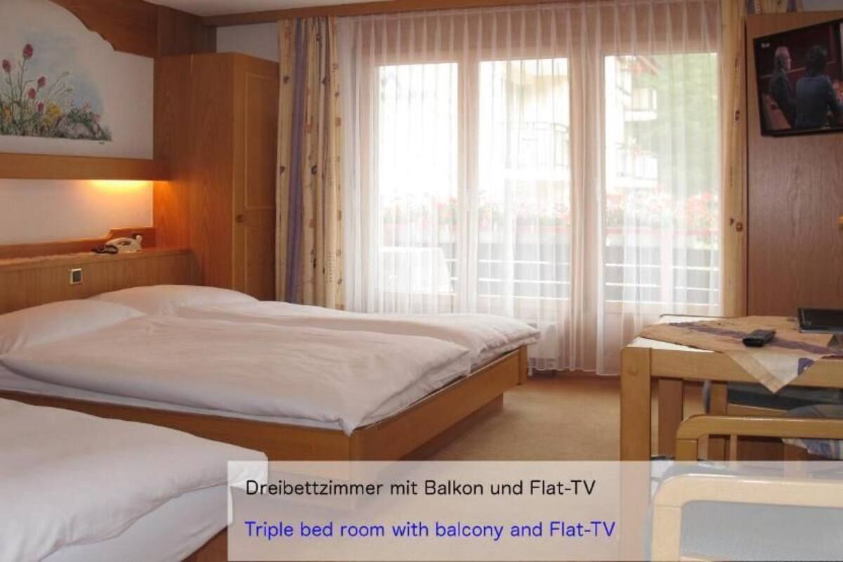 A triple bed room with a balcony and flat-TV.