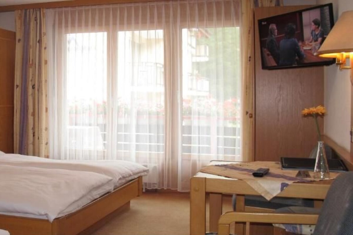 Quarto triplo com varanda e televisão de tela plana.