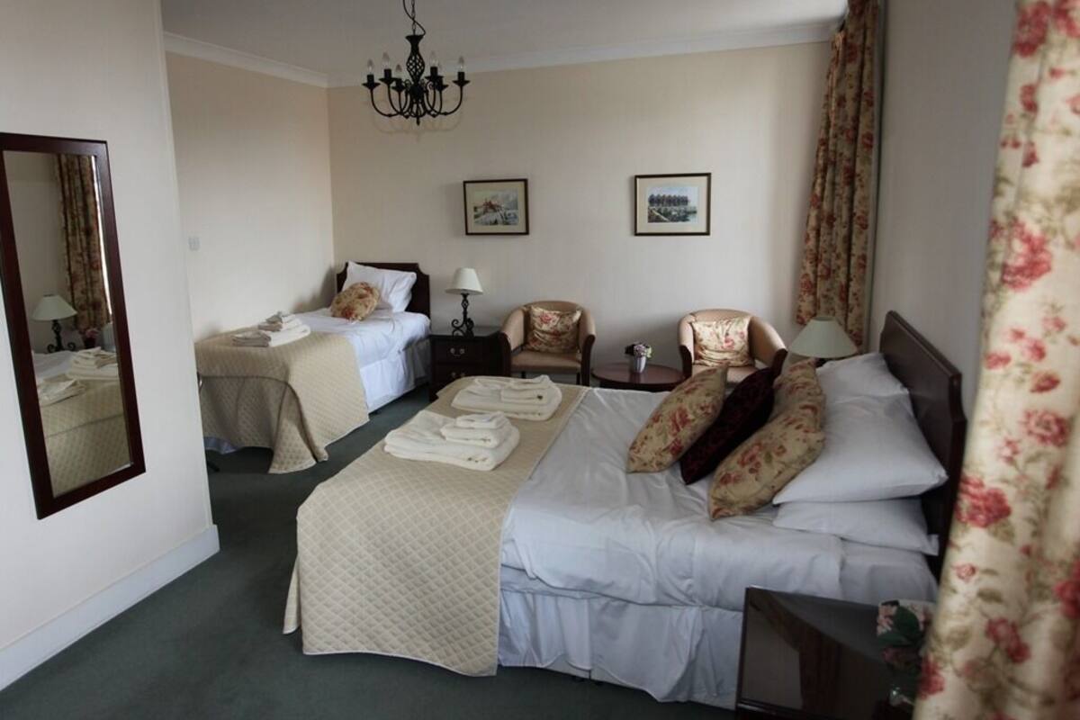 Ein Hotelzimmer mit zwei Betten, einem Chandelier, einem Spiegel und zwei gerahmten Bildern an der Wand.