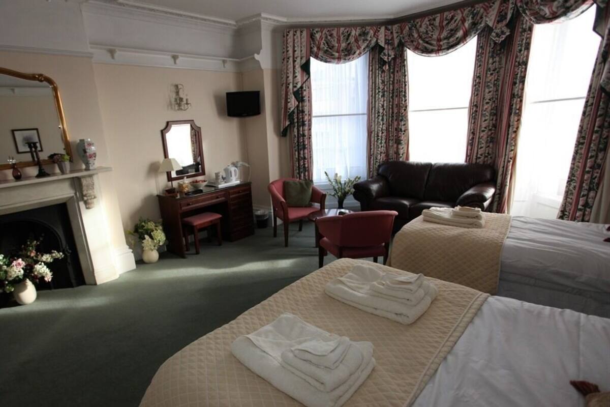Ein Hotelzimmer mit Bett, Schreibtisch, Sessel, Kamin und Fernseher.