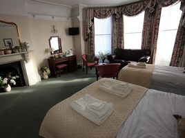 Una habitación de hotel con una cama, un escritorio, una silla, una chimenea y un televisor.