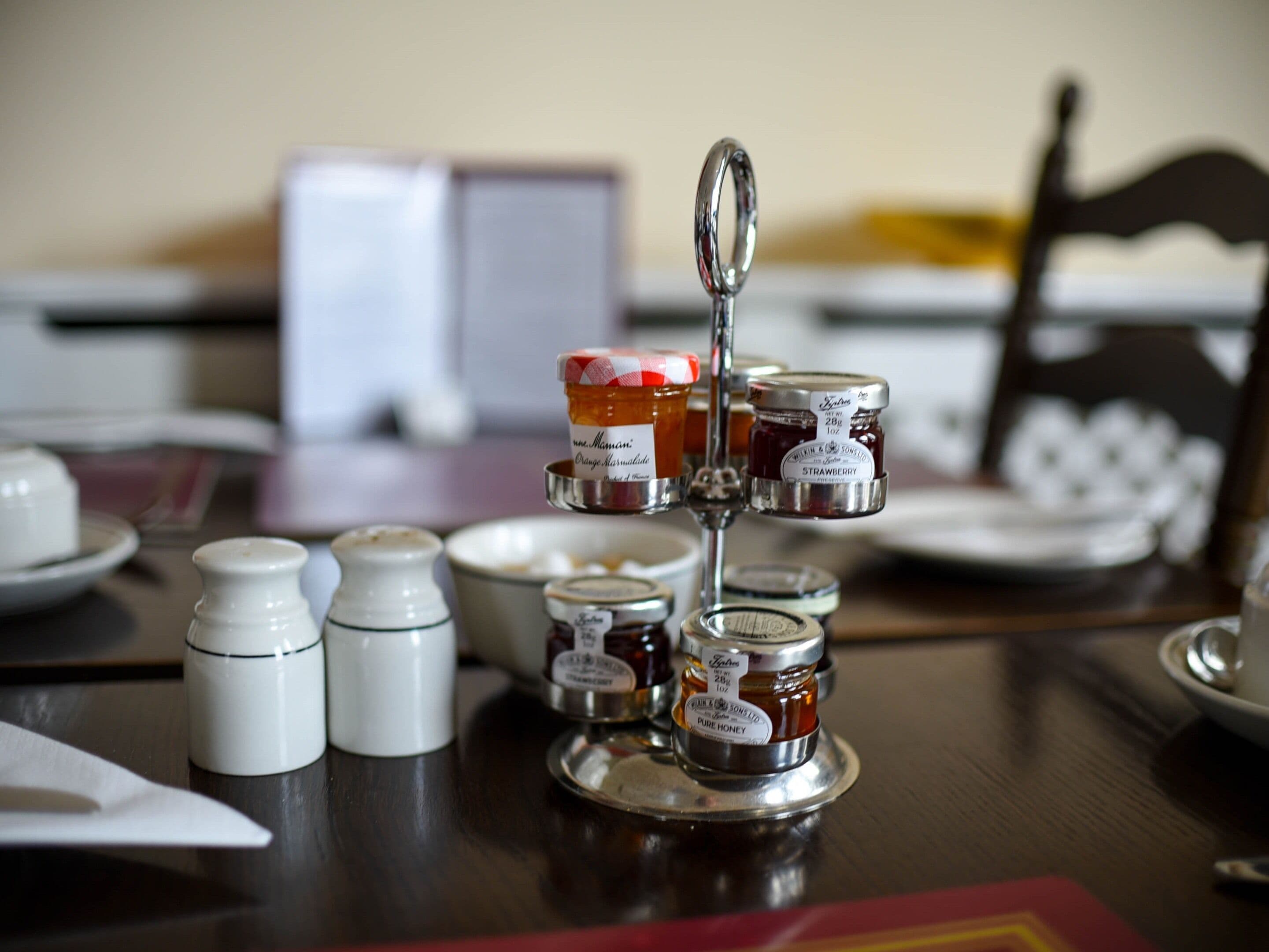 A table with jars of honey and spices, a salt shaker, and a pepper shaker.