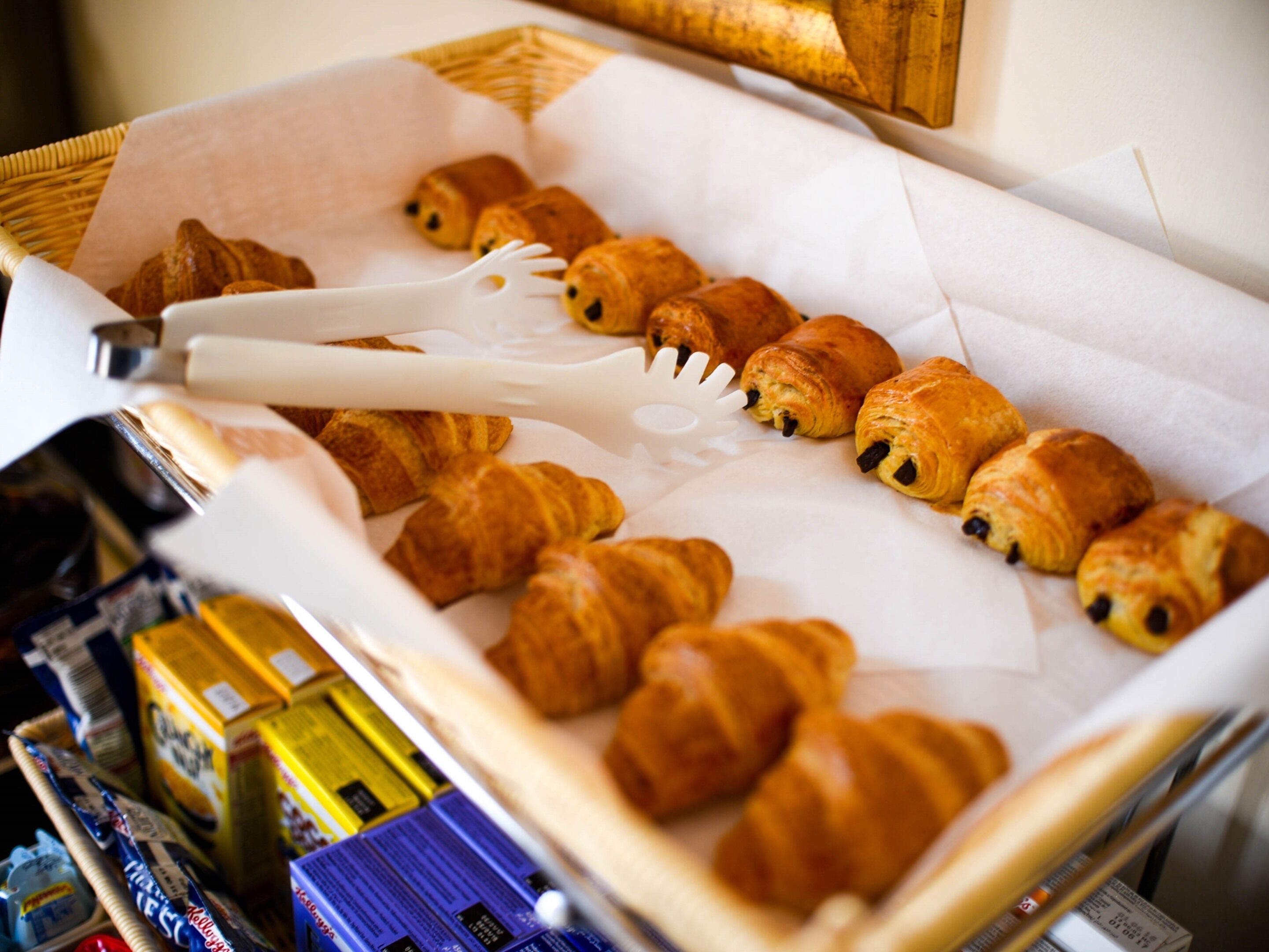 Eine Auswahl an Gebäck, darunter Croissants und Schokröllchen, auf einer weißen Papierunterlage.