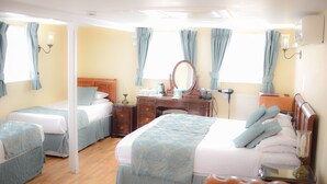 A hotel room with two beds, a wooden dresser, a mirror, a desk, and a chair. - Castle House Hotel (Canterbury)
