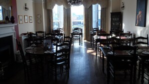 A dining area with multiple tables and chairs, a chandelier, and a fireplace. - Castle House Hotel (Canterbury)