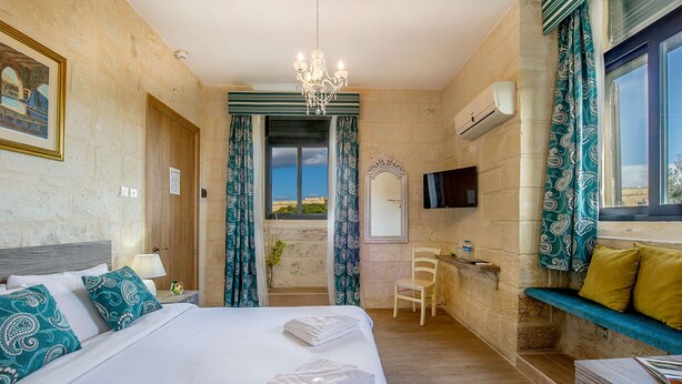 A hotel room with a bed, a desk, a chair, a TV, and a view of the sea. - Point de Vue (Rabat)