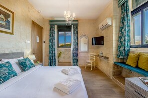 A hotel room with a bed, a desk, a chair, a TV, and a view of the sea. - Point de Vue (Rabat)