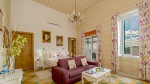 A room with a bed, a sofa, a table, a chandelier, and a window with curtains. - Point de Vue (Rabat)