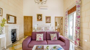 A room with a checkered floor, a fireplace, a bed with floral bedding, and a chandelier. - Point de Vue (Rabat)