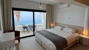 Une chambre d’hôtel moderne avec un grand lit, un bureau et une vue sur l’océan.
