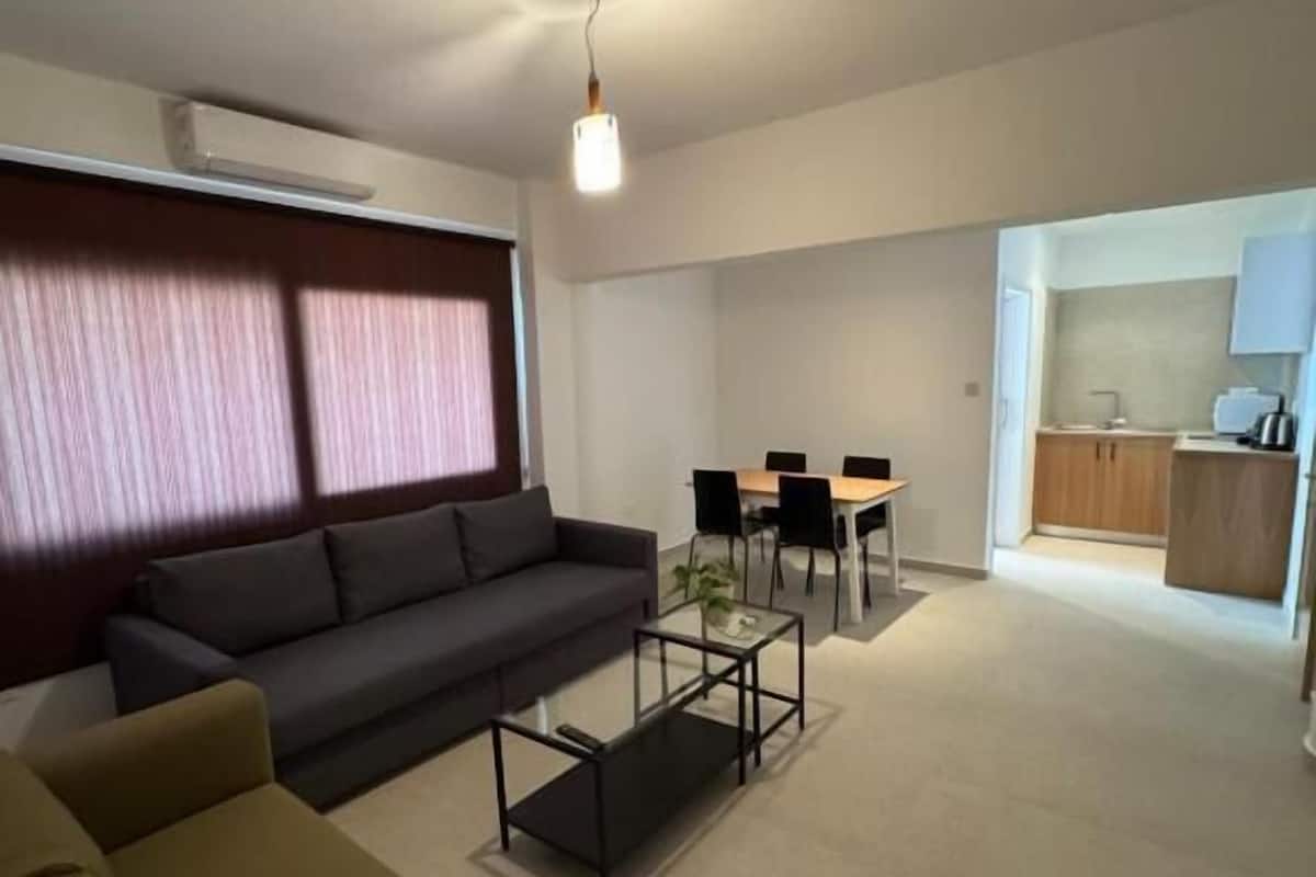 A modern living room with a sofa, coffee table, and dining area.