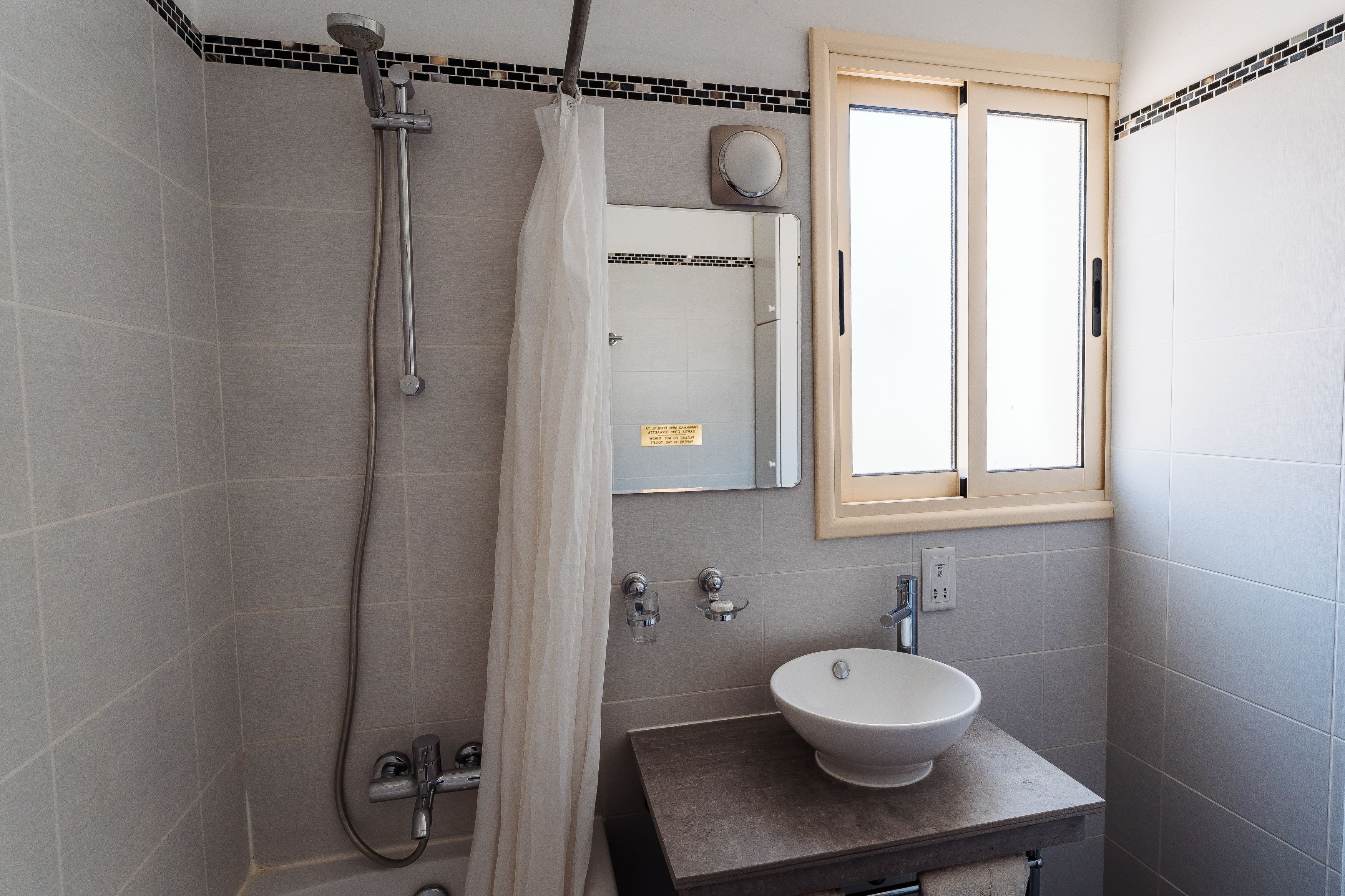 Une salle de bain avec une douche, un lavabo et un miroir.