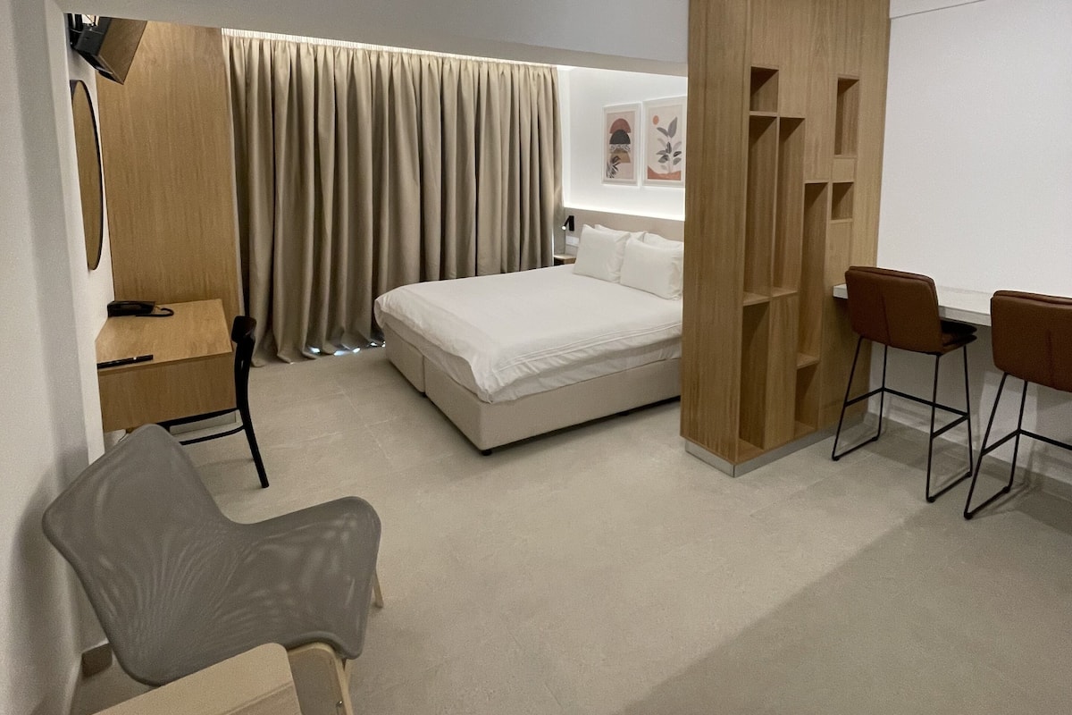 A modern bedroom with a bed, a desk, a chair, and a wardrobe.