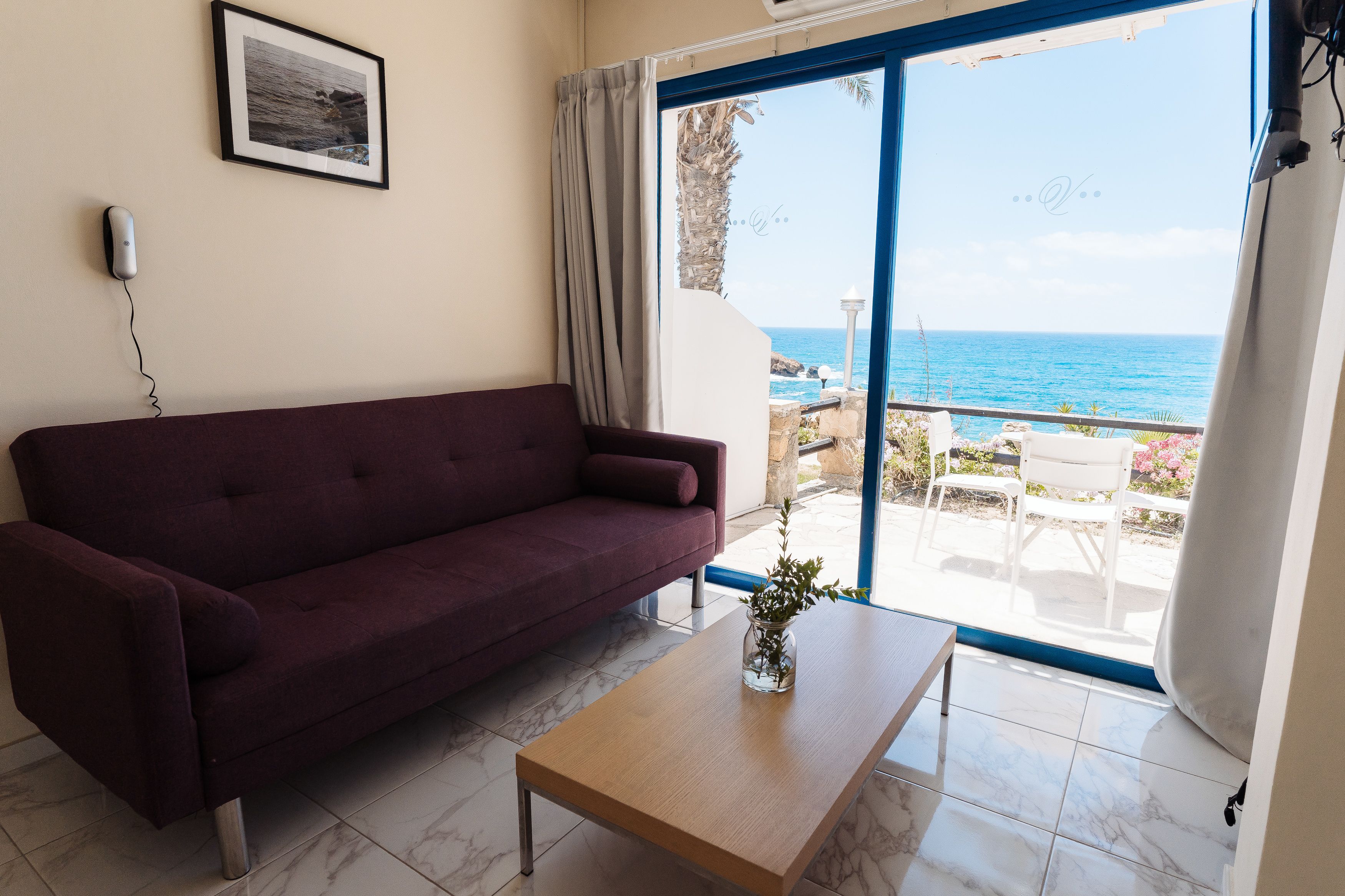 Quarto com sofá, mesa de centro e vista para o mar através de uma grande janela.