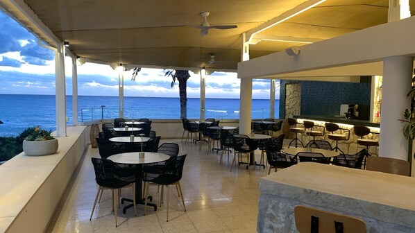 Ein Restaurant am Meer mit Terrassenplätzen, großen Fenstern und Blick auf den Ozean.