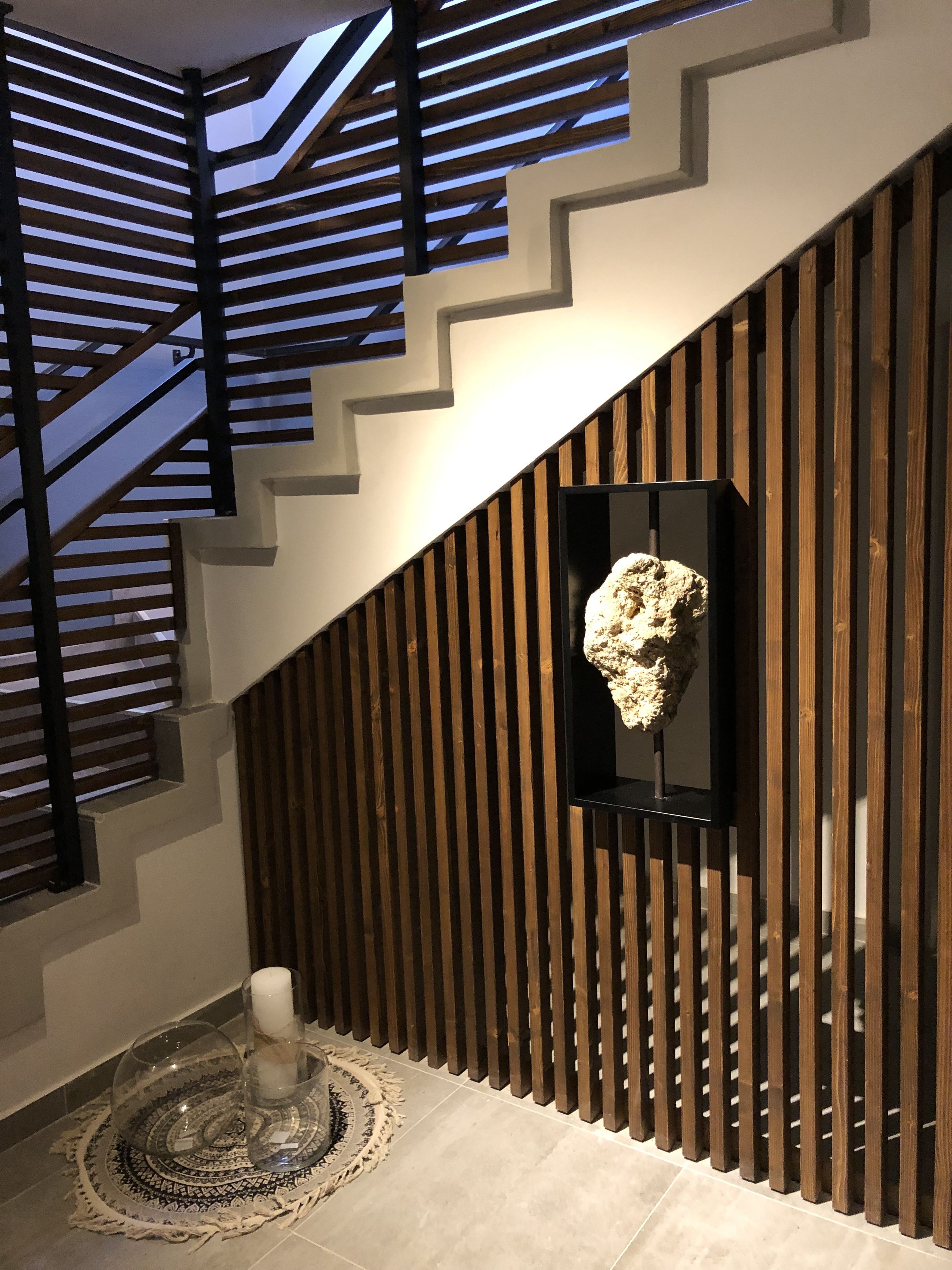 En modern trappa med träpanel och en geometrisk takdesign.