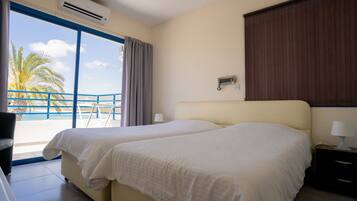 Een hotelkamer met twee bedden, een balkon met uitzicht op palmbomen en een airconditioning.
