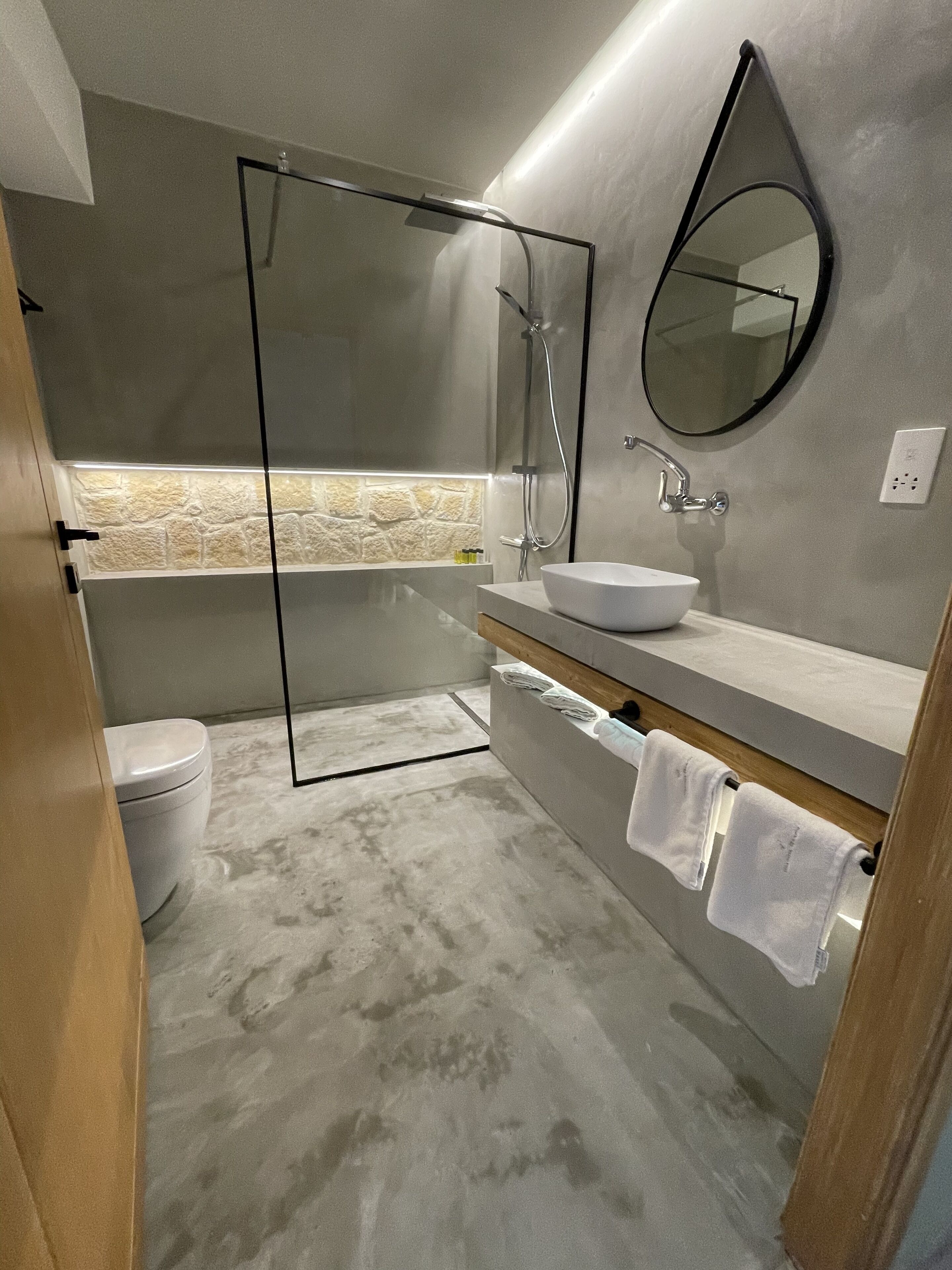Een moderne badkamer met een douchecabine van glas, een vrijstaand bad, een witte wastafel en een grote spiegel.